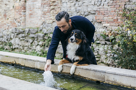 成年男子带着狗狗在水槽中洒水图片