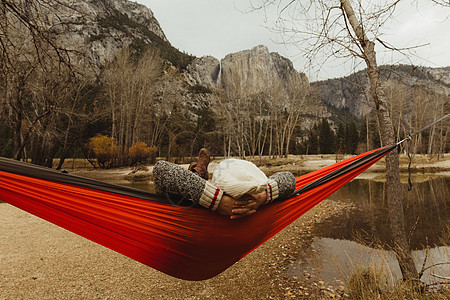 美国加利福尼亚州约塞米蒂公园一名躺在红色吊床上眺望风景的妇女的后视图图片