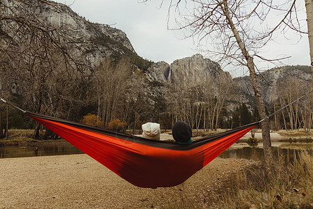 美国加利福尼亚州约塞米蒂公园一对躺在红色吊床上眺望风景的夫妇的后视图图片