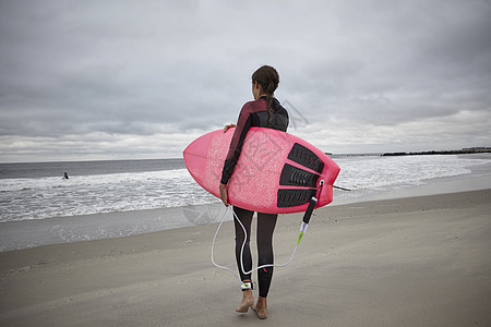 在沙滩上夹着冲浪板的女人图片