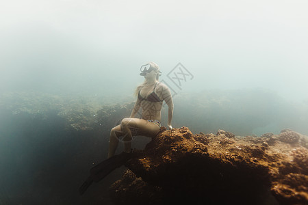 坐在水底岩石上的女性图片