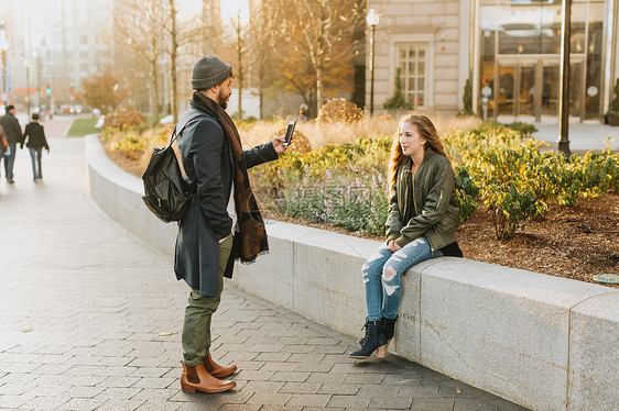 美国马萨诸塞州波士顿市男人给坐在花坛边的女友拍照片图片