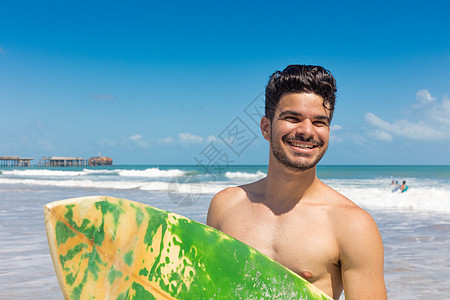 海滩上持有冲浪板的青年男子肖像图片