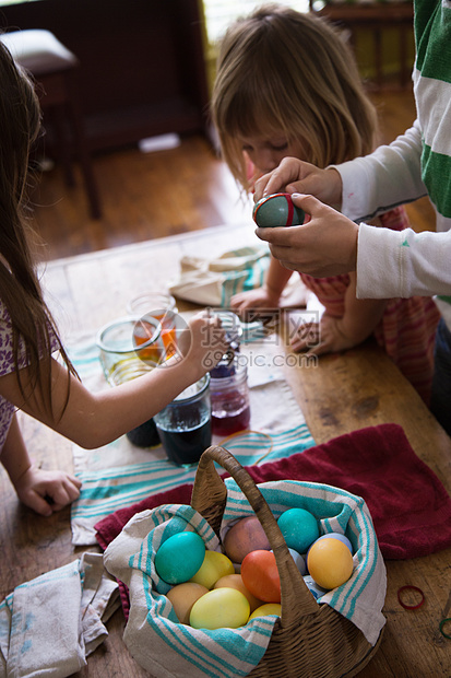 男孩和两个姐妹在桌上染复活节彩蛋图片