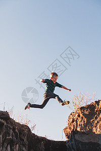 男孩从悬崖上空中跳过图片