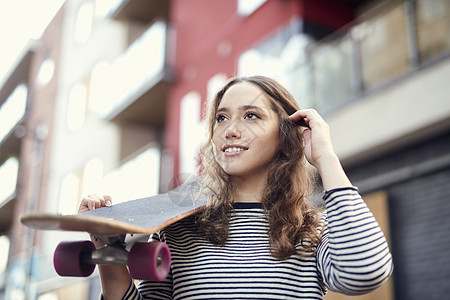 布里斯托尔年轻女滑板员肩扛着滑板背景