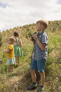 三名幼儿在户外探险男孩拿着望远镜图片