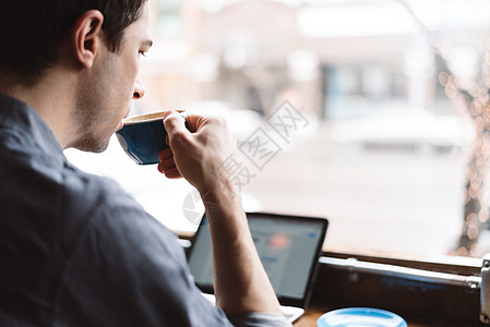 在咖啡馆喝咖啡使用笔记本电脑工作的成年男性图片