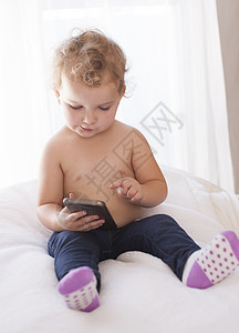 坐在床上拿着手机触摸的女幼儿图片