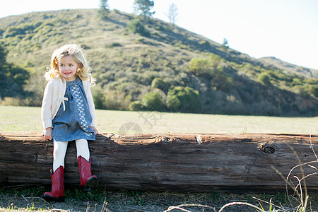 穿着红色牛仔靴坐在原木上的女孩形象图片