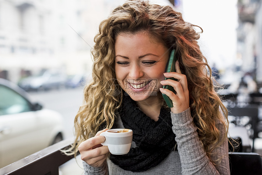 咖啡厅里的女人拿着咖啡杯笑着打电话图片