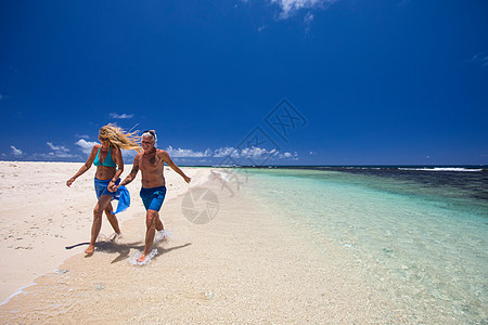 毛里求斯一对成年夫妇手牵着手沿着海滩散步图片