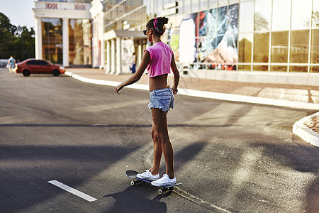年轻女子在路上玩滑板后视图片