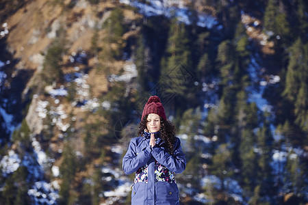 戴针织帽的女子在雪山前冥想图片