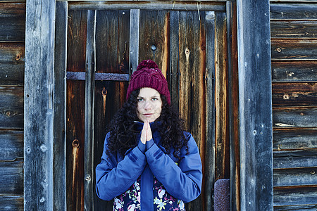 戴着编织帽的女人在木屋门旁冥想图片