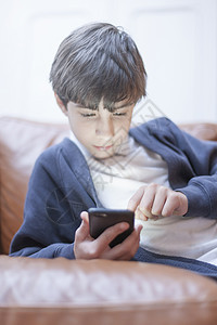 在沙发上玩手机的男孩图片