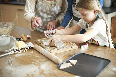 老妇人和孙女在厨房做圣诞树饼干图片