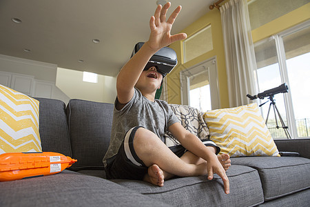 男孩在沙发上玩VR游戏图片