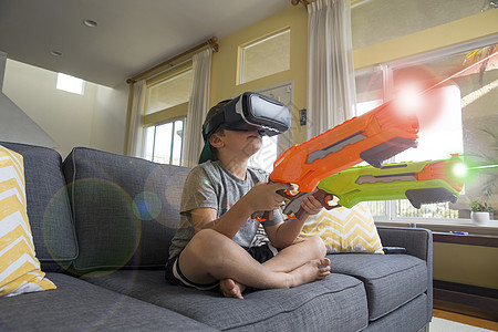 男孩在沙发上玩VR游戏图片