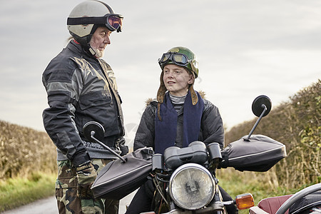 老年男摩托车手与在农村路边骑摩托车的孙子交谈图片