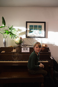 坐在钢琴旁的男孩图片