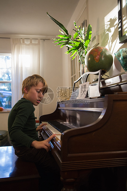 男孩在客厅里弹钢琴图片