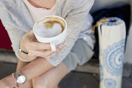 女人在城市人行咖啡厅端着咖啡的手图片