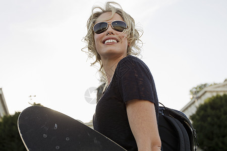 在公园带着滑板微笑的女人图片