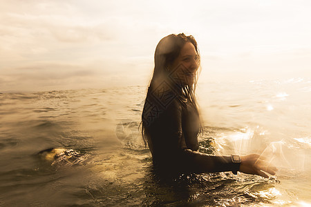 坐在冲浪板上的海年轻女子图片