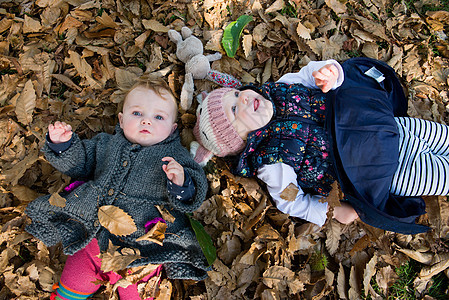 女幼儿和婴头部肖像躺在公园秋叶图片