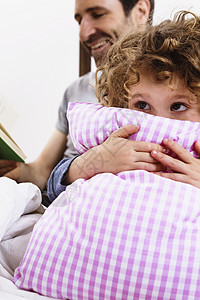 女孩抱着枕头听父亲讲故事图片