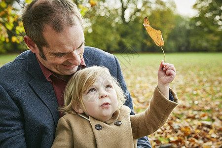 女儿坐在父亲的膝上抱着秋叶图片
