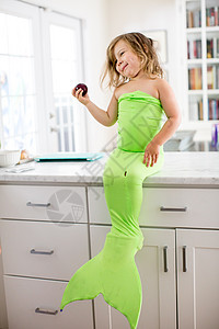 坐在厨房柜台上的绿色美人鱼服装图片