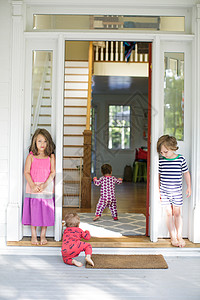 男孩和女孩在门口看着更小的孩子爬进屋里图片