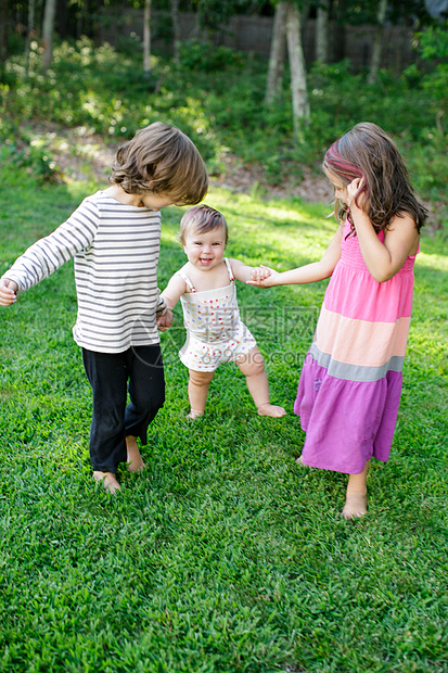 男童和女童在花园中牵着更小的幼儿图片