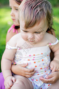 坐在花园里女孩膝盖上的婴儿图片
