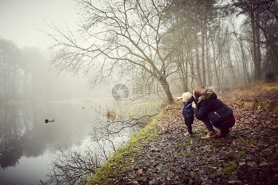 蹲在湖边看的风景的妈妈和孩子图片