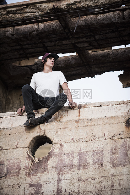 年轻人坐在被毁坏的矿山墙上图片