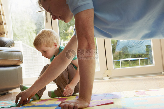 男孩和父亲玩地板拼图游戏图片