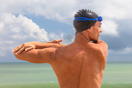 在海滩暖化时雄肌肉游泳运动员的近视图片