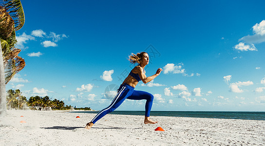 年轻女培训在海滩上练锥体之间运行图片
