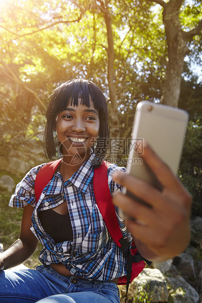 森林中的年轻妇女使用智能手机有视频电话南非开普敦图片