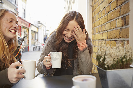 两个女朋友坐在户外喝咖啡笑图片