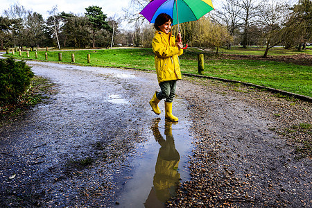 黄色的阿诺拉克男孩带着雨伞在公园里图片