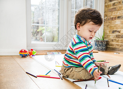 男幼儿坐在地板上用长纸画图片