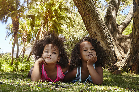两个年轻姐妹的肖像躺在树旁的草上图片