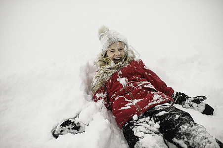 微笑的女孩躺在背上满身是雪图片