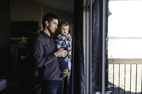 男人和小孩的儿子在家里看着窗户图片