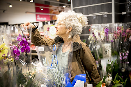 超市的老人看着植物和花朵图片