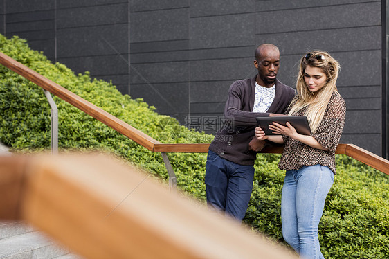 年轻商人和女人在城市楼梯上看平板电脑图片